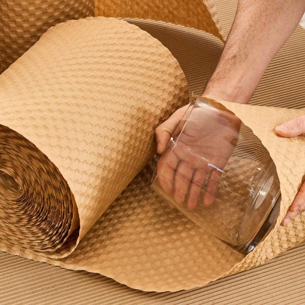 Glass jar being wrapped in embossed kraft paper bubble cushioning