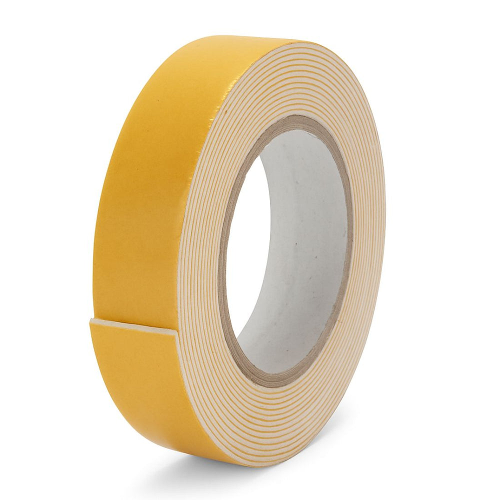 Double sided foam mounting tape 24 mm roll with the yellow liner peeled back from the white foam