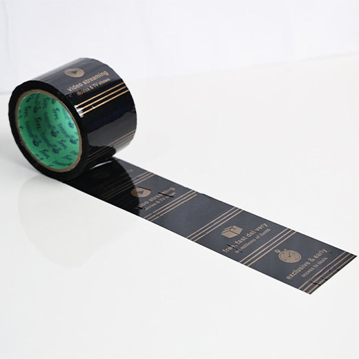 Printed packaging tape for Amazon sellers, 3 inch black roll unwound to show the gold print pattern